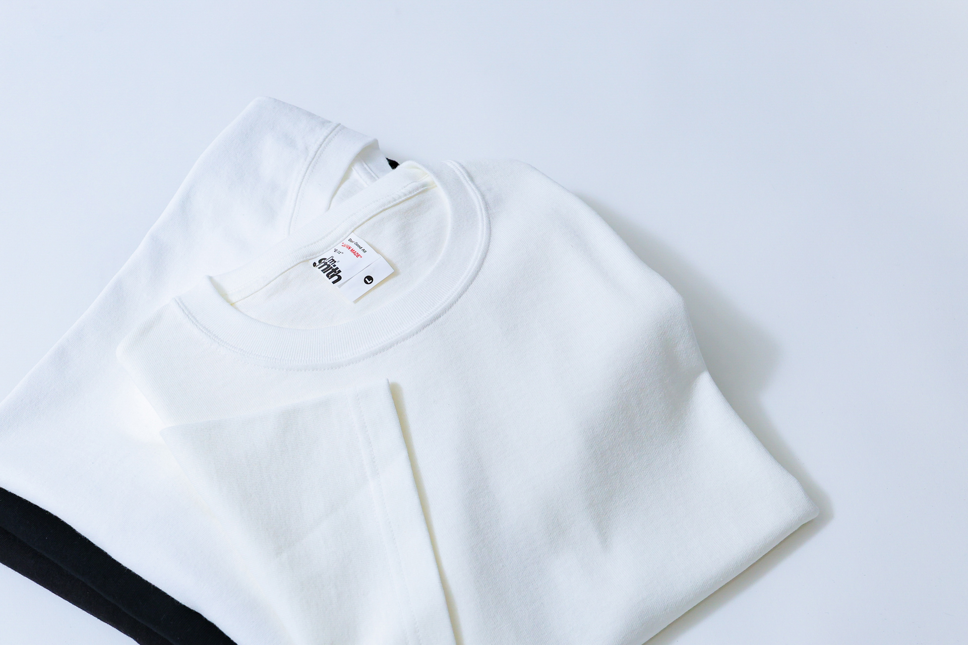 重ねて置かれた白いI'm Smith Tシャツ